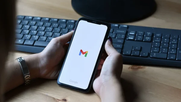 Mano con smartphone e logo Gmail aperto.