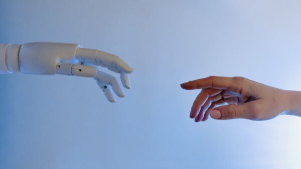 Mano umana raggiunge un robot simboleggiando il futuro AI dei gestionali