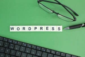 laptop keyboard, glasses and pen with Wordpress alphabet words.