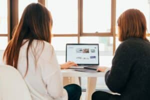 deux femmes discutent en regardant un ordinateur portable