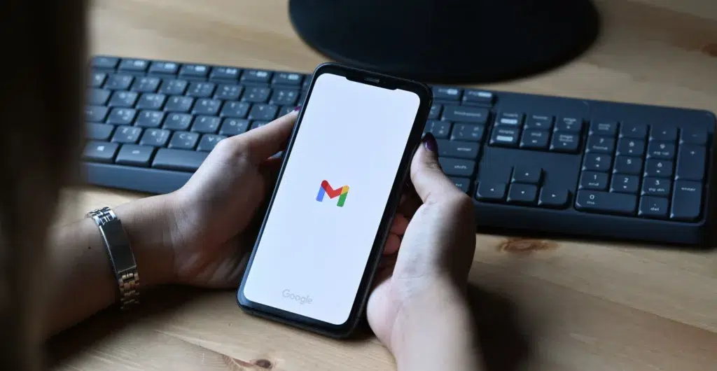 Hand mit Smartphone und geöffnetem Gmail-Logo.