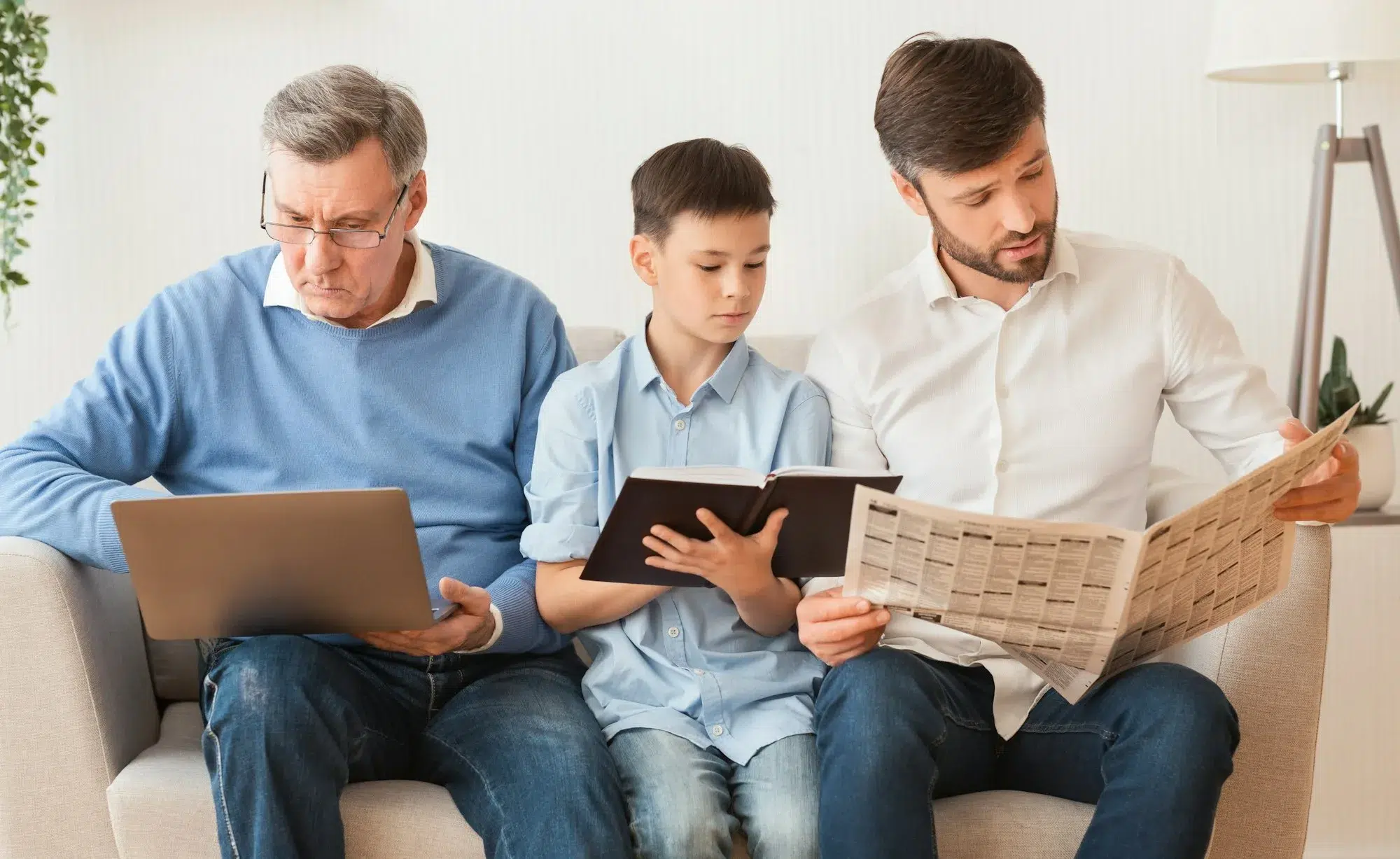 Familia masculina que utiliza ordenadores portátiles y lee libros y periódicos en casa